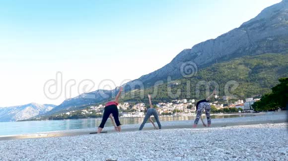三个女人早上在亚得里亚海海边练习瑜伽视频的预览图