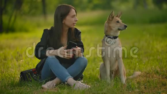 女孩在她的狗旁边的智能手机上自拍视频的预览图