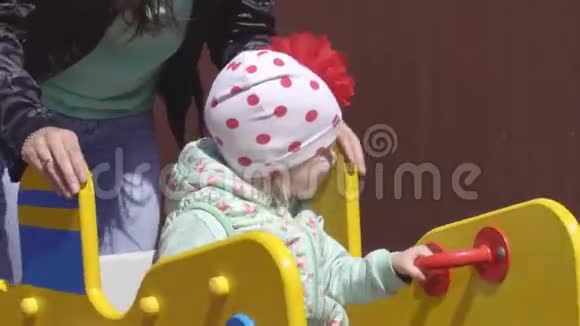 3岁的白种人小女孩和她的母亲在一个现代化的儿童游乐场玩春秋千视频的预览图