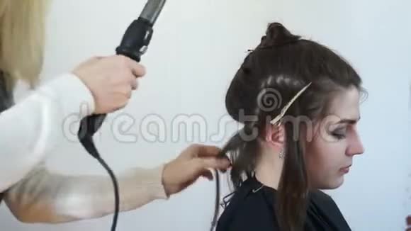 造型师用弯曲的铁把头发卷起来视频的预览图