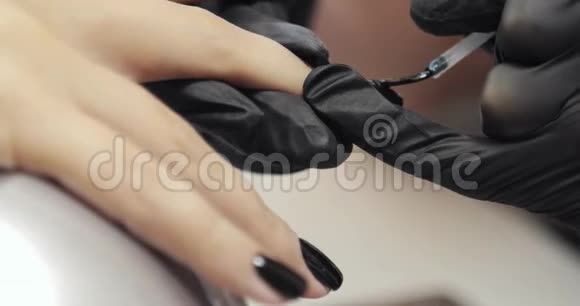 女人在美容院用黑色虫胶修甲手特写视频的预览图