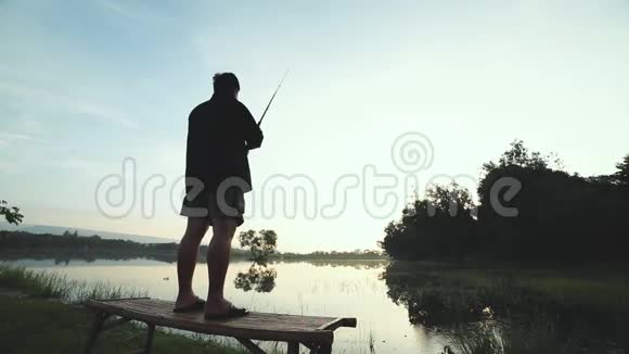 一个人拿着鱼竿独自站在湖边钓鱼的剪影视频的预览图