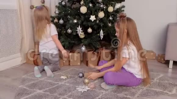 两个姐妹一起玩玩具星星和球坐在圣诞树附近视频的预览图