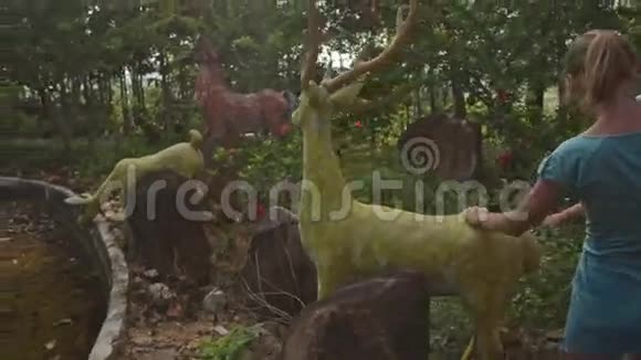 热带公园鹿雕塑上的小女孩攀爬视频的预览图