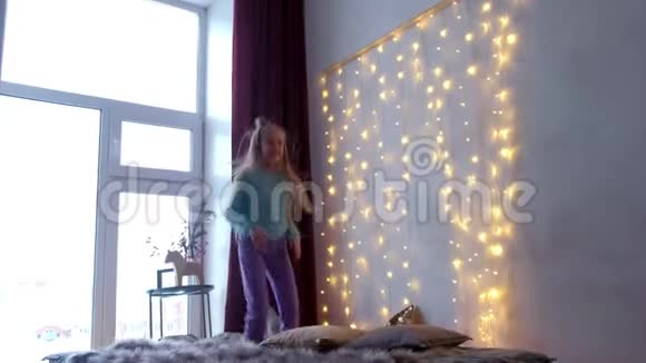 快乐的十几岁女孩在圣诞室内用大窗户玩跳床游戏视频的预览图