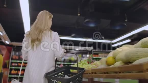 回头看一个女孩手里拿着一个篮子在超市里走来走去想着货架上的水果视频的预览图
