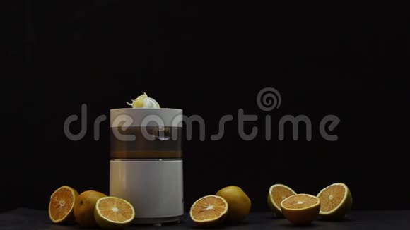 在榨汁机里用手在黑色背景上压榨橙子视频的预览图