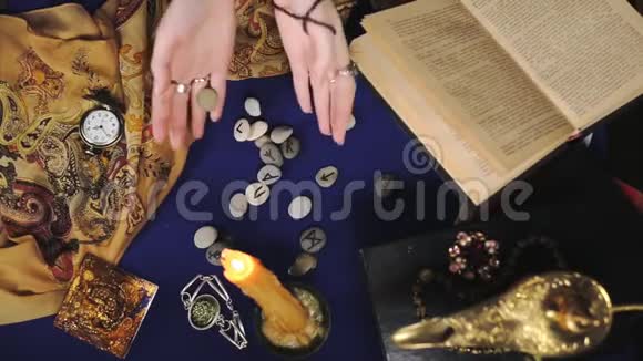 占星术和神秘主义一位女算命先生把符文扔到桌子上读它们读一本书从上面看到的视频的预览图