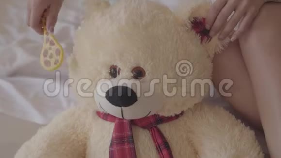特写小女子用小刷子刷大熊玩具在家里休闲家庭视频的预览图