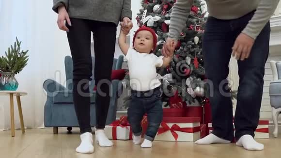 一张漂亮的家庭照片手牵着他们甜蜜的婴儿和他一起在装饰的房间里散步视频的预览图