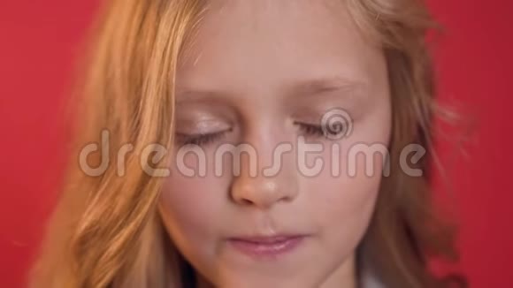 红发和蓝眼睛在红色背景上摆姿势的严肃漂亮少女视频的预览图