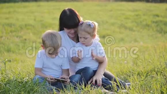 快乐的家庭妈妈和孩子们在公园的户外玩得很开心一群使用智能手机的兄妹视频的预览图