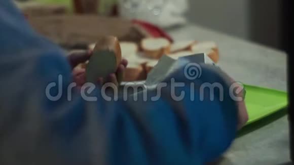 在聚会上男人的手把黄油涂在切碎的面包上后面的摄像头视频的预览图