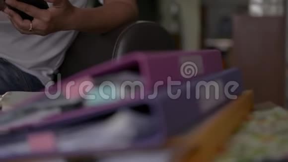 女士穿着休闲装坐在一个皮革沙发上使用手机并在家里处理一堆文件视频的预览图