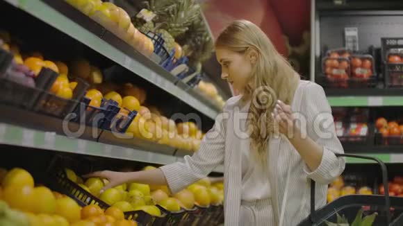 在杂货店手工挑选柠檬的妇女在超市的水果和蔬菜通道挑选柠檬视频的预览图