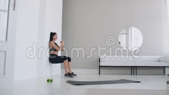 一个处于静止位置的女人以坐姿靠在墙上进行一项艰苦的练习耐力视频的预览图