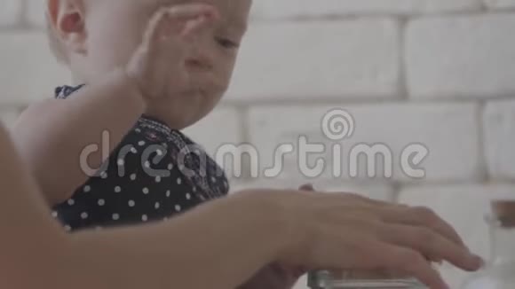 她母亲在帮她的时候孩子正在玩麦片粥的特写镜头厨房里的年轻女子视频的预览图
