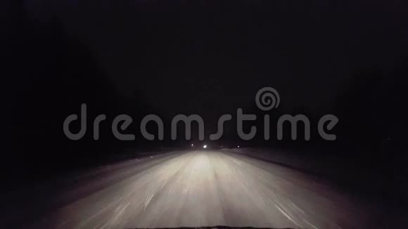 在暴风雪中驾驶迎面而来的车辆灯在夜间接近乡村道路POV移动方向的驱动点视频的预览图