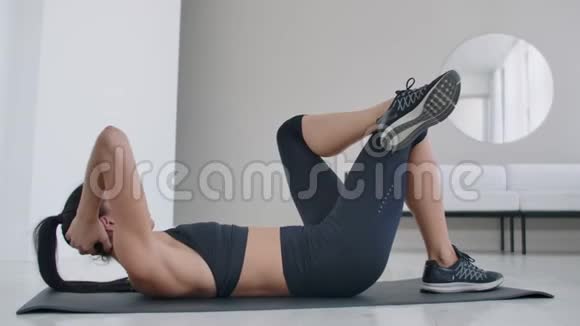 白人黑发女人躺在地毯上做腹肌锻炼每天在家锻炼身体保持健康视频的预览图