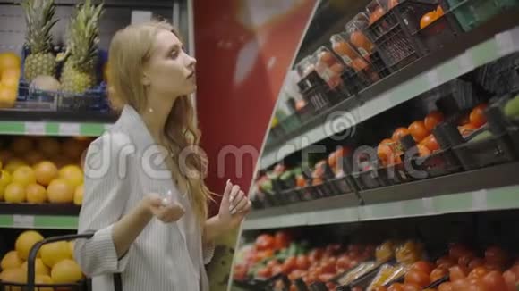 那个女孩家庭主妇在超市购物把新鲜的西红柿放在树枝上放进玻璃纸包里系上领带视频的预览图