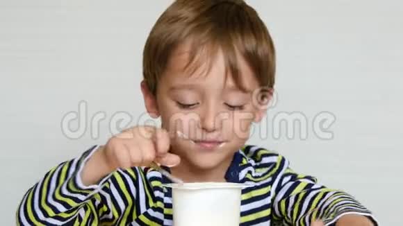 一个可爱的欧洲模样的小男孩正坐在桌子旁吃着奶制品孩子吃酸奶健康视频的预览图