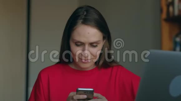 穿红色运动衫的女孩使用智能手机与家人交流视频的预览图