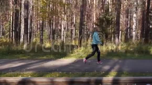 女人在秋天的公园里练习北欧散步从附近的一辆车上运动侧视广角射击视频的预览图