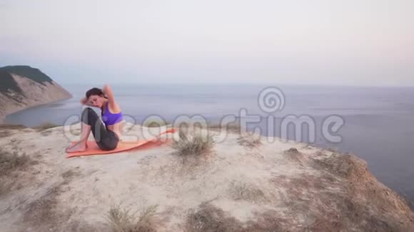 年轻美丽的女子在海边的悬崖上摇晃着压力早晨在山上视频的预览图