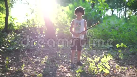 性别中立的孩子正在森林里玩一根棍子对抗夕阳视频的预览图