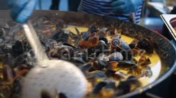 在炒锅里烹制多汁的贻贝关闭厨师手搅拌新鲜软体动物视频的预览图