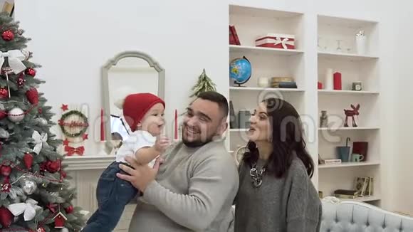 幸福的家庭与可爱的蹒跚学步的孩子一起欢乐地度过节日装饰的圣诞房视频的预览图
