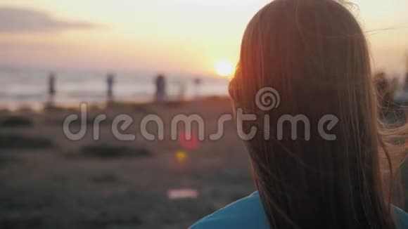 快乐的微笑女孩在海滩上看着大海有着美丽的灯光头发孩子开心地笑着在旁边休息视频的预览图