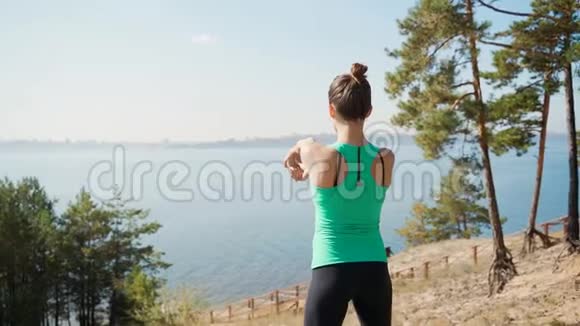 女孩伸展手臂站在河边视频的预览图