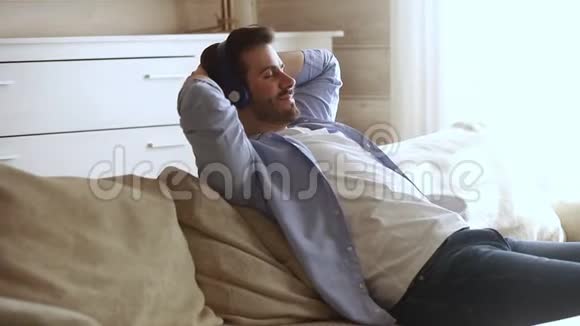 冷静的男人戴着耳机在家听音乐心寒视频的预览图