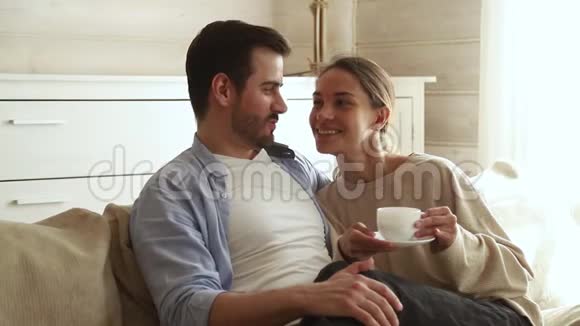 快乐的一对拥抱在沙发上喝咖啡茶视频的预览图
