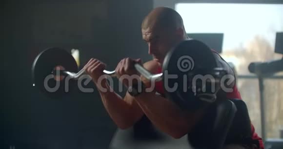 男运动员举起一个体重沉重的杠铃坐在长凳上手的慢动作练习视频的预览图