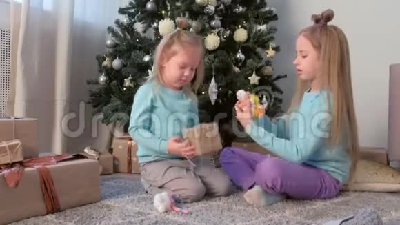 两个女孩姐妹在家里坐在圣诞树附近玩雪人玩具视频的预览图