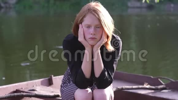 美丽的姜姑娘坐在船上悲伤视频的预览图