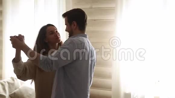 快乐浪漫的年轻夫妇享受客厅的慢舞视频的预览图