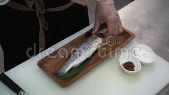 一位男士厨师在餐厅厨房的新鲜鱼上添加香料视频的预览图