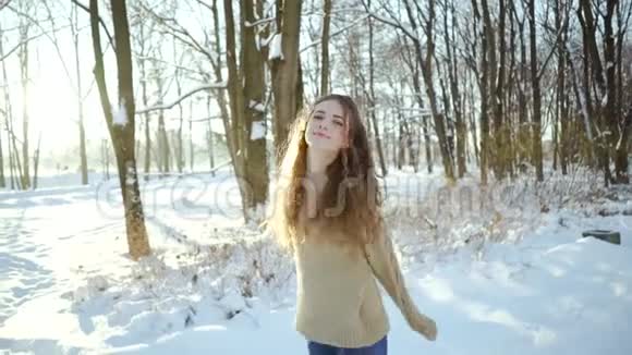 穿着毛衣的漂亮女孩在寒冷中玩得很开心一个穿着温暖衣服穿着雪衣服的卷发少女视频的预览图