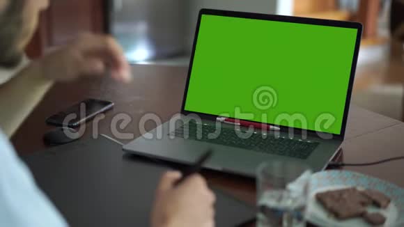 高技能的白种人留着胡子在办公室里使用图形平板电脑和笔记本电脑男工看绿屏手绘视频的预览图