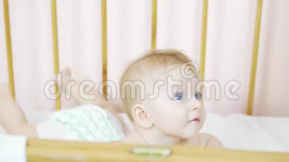 一个迷人的蓝眼睛新生儿躺在婴儿床上看着相机视频的预览图