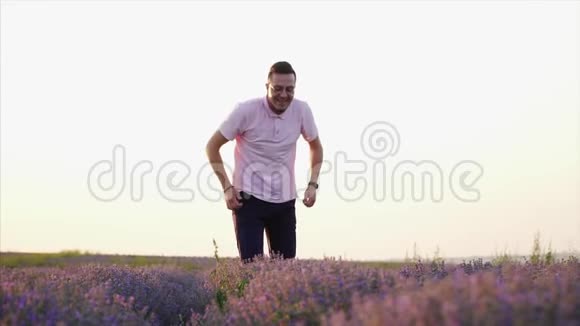 快乐的男人在花薰衣草地跳跃慢动作视频的预览图