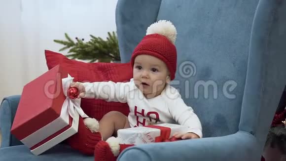 奇妙的幼儿坐在大扶手椅上玩圣诞礼物视频的预览图