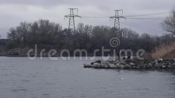 多云沉闷的一天人的夹克站在河岸上电力线背景视频的预览图