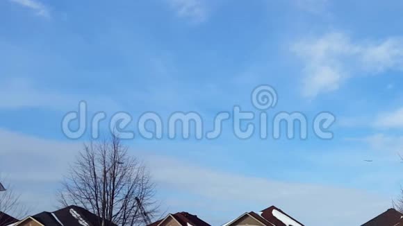 飞机在蓝天中飞过住宅楼的远景商用飞机飞行升空和爬升视频的预览图