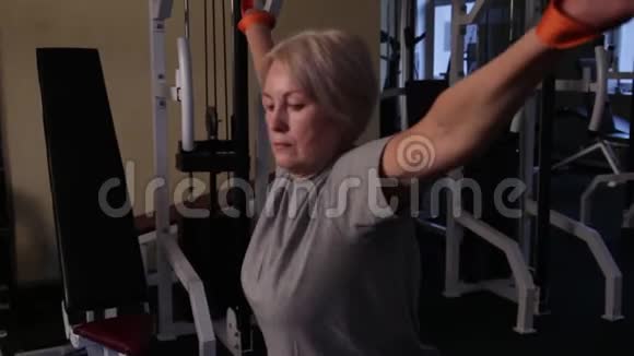 老年妇女做运动在交叉模拟器上扭动身体靠近侧视视频的预览图