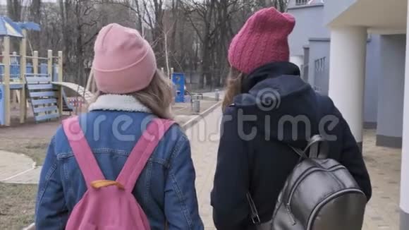 两个会走路的女孩穿着帽子外套带背包的夹克后景视频的预览图