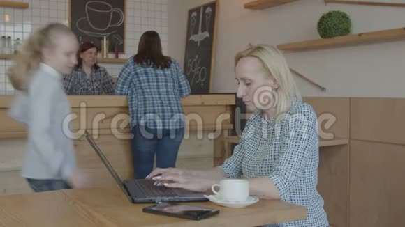 普雷特女孩把忙碌的妈妈从咖啡馆里的笔记本电脑上撕下来视频的预览图